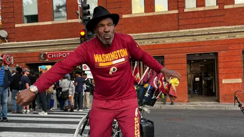 William Ward, 65, wears a hat and red tracksuit. 