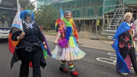 KIT TAYLOR/BBC People taking part in the parade, wearing outfits filled with different colours and patterns.