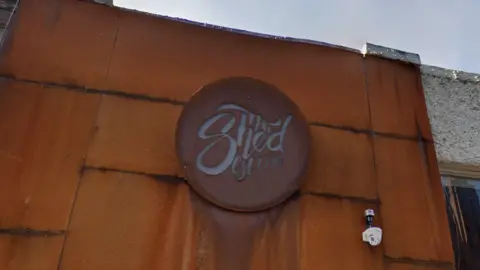Google A rusted metal sign for The Shed