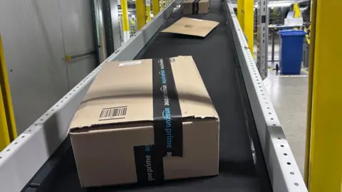 An Amazon box on a conveyor belt inside a warehouse