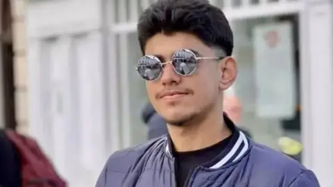 Ahmad aged 16, in Dover, wearing sunglasses and a navy blue jacket.