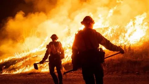 Firefighters work as the Hughes Fire burns