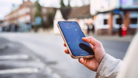Getty Images Close up of a hand holding a phone with a map on it