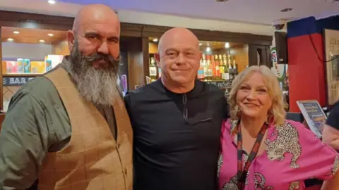 Jackie Henson Martin and Jackie Henson either side of Ross Kemp in front of a bar