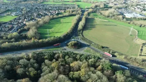 National Highways Aerial view of the existing A46 Walsgrave junction. A roundabout sits in between two fields, with houses seen beyond the fields in the distance.