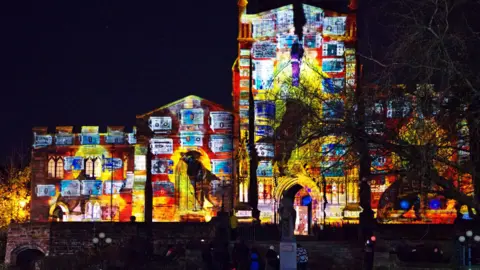 Graham Stubbs/Asylum Artist Quarter CIC A building lit up with colourful lights and art work. 
