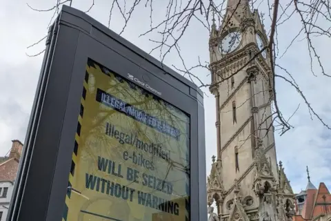 Leicestershire Police A digital screen with a yellow warning displayed in the shadow of the Clock Tower