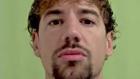 A police mugshot of Kane Jones, who has tousled dark hair, a goatee beard and brown eyes.