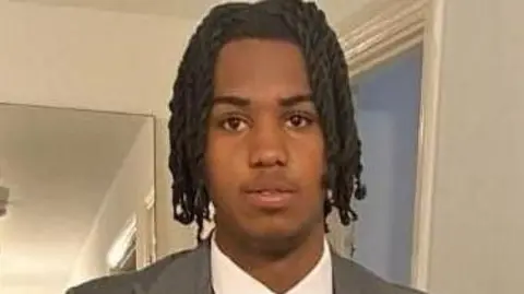 Pictured is Kamari Johnson, 16, wearing a suit jacket and a white shirt