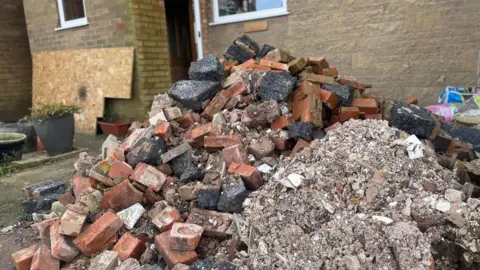 Simon Thake A huge mound of building waste made up of bricks in front of a modern house