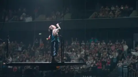 Paramount Pictures UK Billie Eilish singing on a raised platform with thousands of fans in the background