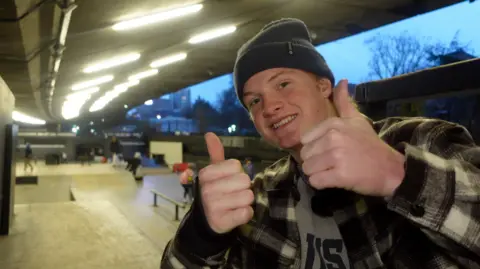 Cunningham, pictured at BAYSIXTY6 skatepark, London, holding both thumbs up with various skatebaorders in the background