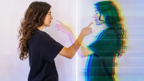 Getty Images A lady points to a reflection of herself
