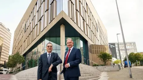 University of Strathclyde Charles Huang and Prof Sir Jim McDonald, the university's principal and vice-chancellor, stand in front of the steps leading to a university building. 