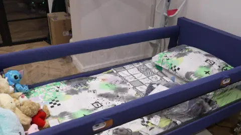 A child's bed on a wood floor with rails on either side of it