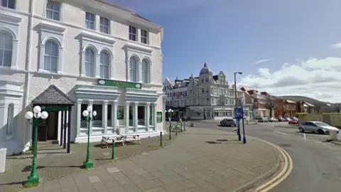 White-washed three-storey Nevill pub in Llandudno. You can see the road and pavement outside the building. 