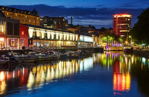 Lights from buildings on Bristol's harbourside reflected in the water at night
