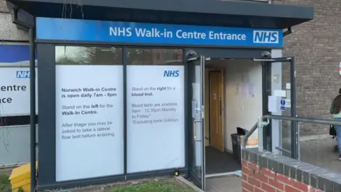 The entrance to Norwich's NHS walk-in centre. There is an automatic door and a large window to the left.