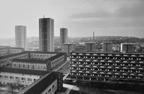 Getty Images A black and white photo of multi storey blocks of housing, with three very high rise blocks in the rear of the picture