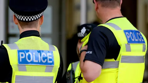 Joe Giddons/PA Wire Two police officers facing away from camera