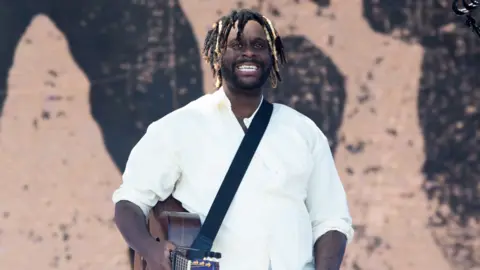 Getty Images Myles Smith wears a white shirt and smiles whilst performing during Radio 1's Big Weekend at Herrington Country Park on May 23, 2026 in Sunderland.