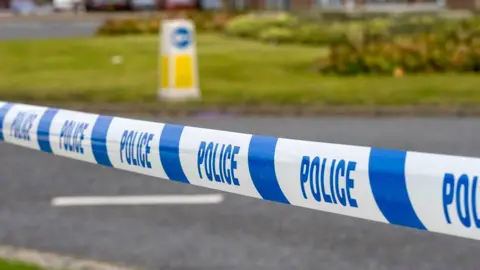 Blue and white police tape around roundabout and road