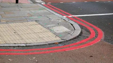 Double red lines wrap around a corner of a roadside.