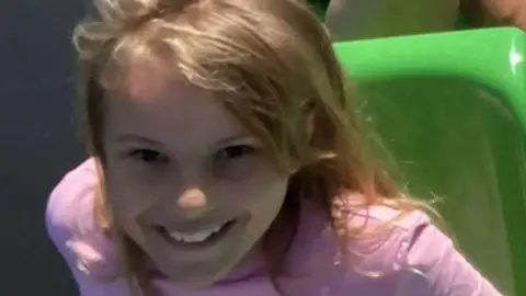 Lilia Valutyte smiling at the camera with blonde hair and a pink top on.