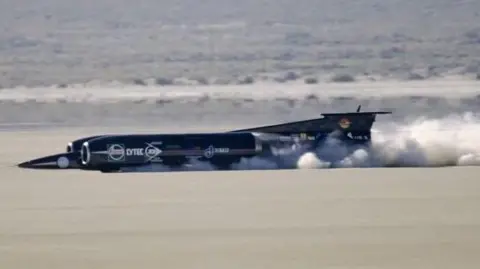 Getty Images A four-wheeled car which looks more like an aeroplane. It has a concorde-style nose and gaping air intakes at the front. The rear is obscured by its exhaust gasses
