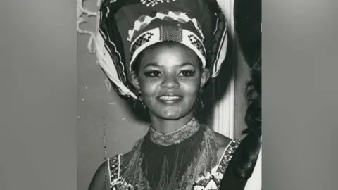 Shutterstock A black-and-white portrait image of Cynthia Shange smiling and wearing cultural clothing and and a headdress