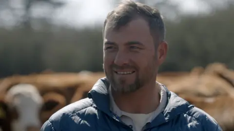 BBC A head and shoulders image of farmer Marthinus. He is wearing a blue puffer jacket and a blue shirt and white vest can be seen underneath it.