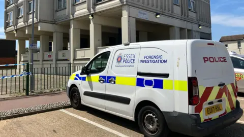 Henry Godfrey-Evans/BBC A white police forensics van parked in front of the large tower.