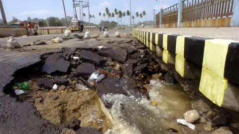 Getty Images Sebuah gambar yang diambil pada 28 Desember 2004 menunjukkan jalan tepi pantai yang sebagian runtuh di sekitar Port Blair, ibu kota negara bagian Kepulauan Andaman dan Nikobar di tenggara India. Gelombang besar yang dipicu oleh gempa bumi tanggal 26 Desember, menewaskan sedikitnya 4.000 orang di pulau-pulau tersebut dan menyebabkan ribuan orang hilang dan tak terhitung banyaknya orang yang kehilangan tempat tinggal di India sementara jumlah korban tewas mencapai 8.500 akibat tsunami yang menghantam pantai-pantai yang tidak terlindungi di seluruh Asia.