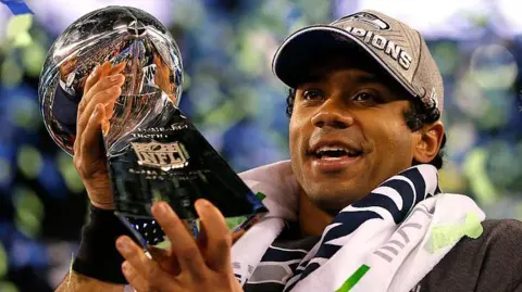 Russell Wilson holding the Lombardi Trophy after the Seattle Seahawks win the Super Bowl in 2014