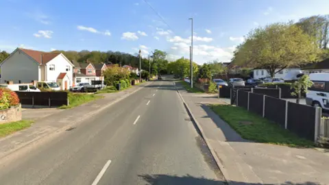 Google Houses lining either side of a stretch of road. A number of them have cars parked in their drives. 