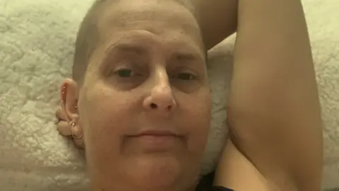 Myeloma UK A woman is looking at the camera with part of her left arm being behind her head.