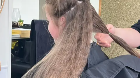 PA Media Lexie Warwick-Oliver having her hair cut off