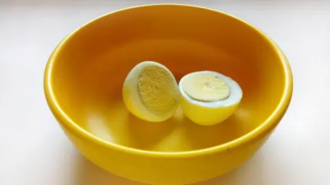 A boiled egg placed in a yellow plastic bowl 