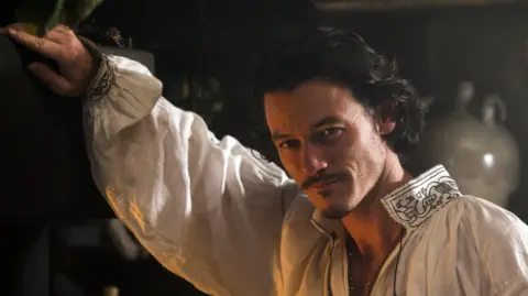 Getty Images Luke Evans smiling in costume of Aramis in The Three Musketeers