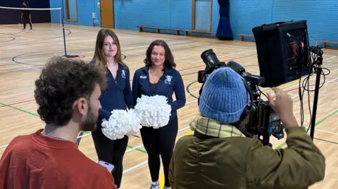 Bournemouth University A cameraman and another film crew member are filming the two women in the gym.