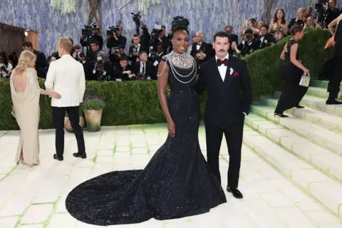 EPA Tennis legend Venus Williams and Italian-Danish actor Alex Preti pose on the red carpet for the 2026 Met Gala.  Williams wears a black, sparkling gown with a flared train, but the star of the outfit is her large silver neck adornment.