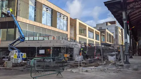 Building work of a £45m entertainment complex in Preston showing building work being finished with a man in hi-vis jacket and helmet in a cherry picker working at the top of one of the buildings