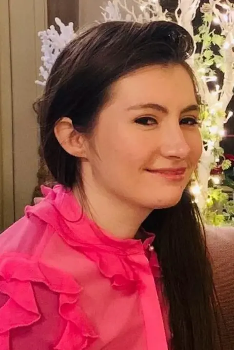 Sarah Cooper-Lesadd A woman in a pink top with brown hair 