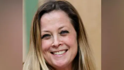 Annabel Rook, a woman with blonde shoulder-length hair, smiles and looks into the camera. 