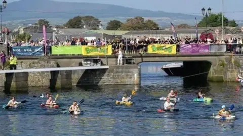 MANX SCENES People in tin baths in Castletown Harbour, with hundreds of spectators watching from a road bridge across the harbour which has banners on it.