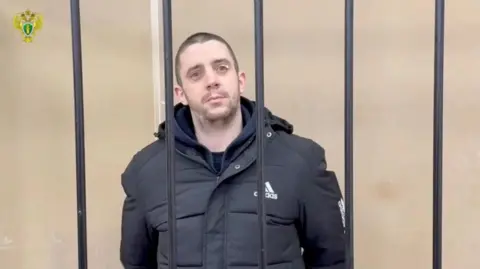 Reuters Hayden Davies seen behind bars in a court room with a shaved head 