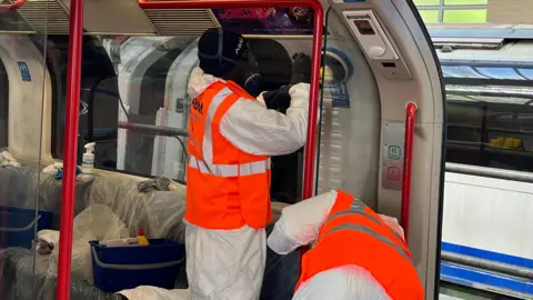Men clean the graffiti inside a train with buffers