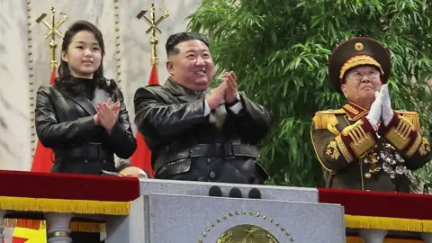 Reuters Kim Jong un standing next to his daughter, Ju Ae. They are wearing leather jackets and clapping, and flanked by officials in ceremonial uniforms