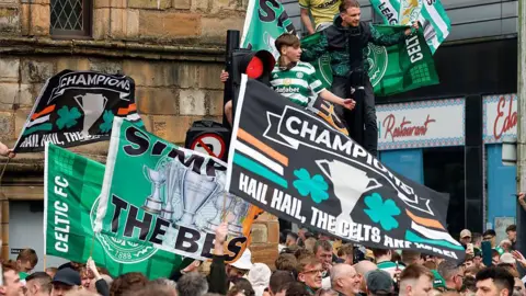 hundreds of celtic flans waving banners in a city centre street