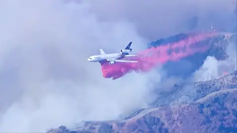 Plane drops fire retardant in path of LA wildfire